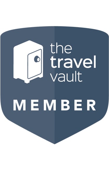 The Travel Vault member badge with a blue shield, white safe icon, and text 'the travel vault MEMBER' in white.