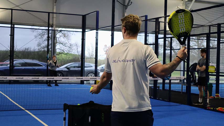 Padel tennis coaching session at a UK clinic with an Active Away coach on a blue court.
