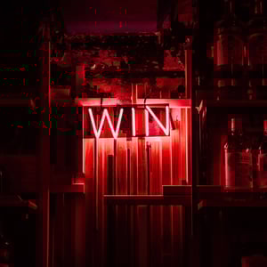 Red neon sign spelling 'WIN' with shelves full of bottles in the background, creating a vibrant and inviting ambiance.