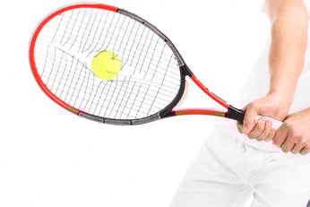 tennis-racket-with-broken-strings_470178-13425 Close-up of a tennis racket with broken strings held by a player in white, featuring a yellow tennis ball during a swing.