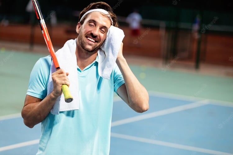 tired-tennis-player-man-tennis-court-with-racket_522218-501 Tired male tennis player on court resting with a towel and holding a racket, wearing a blue shirt and a white headband.
