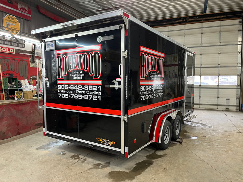 Black Roswood commercial trailer with large logo decals, phone numbers, website lettering, and red accent bands