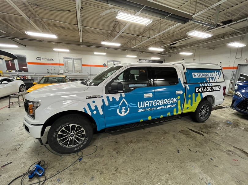 White pickup truck with blue lawn-irrigation graphics integrated with the factory paint