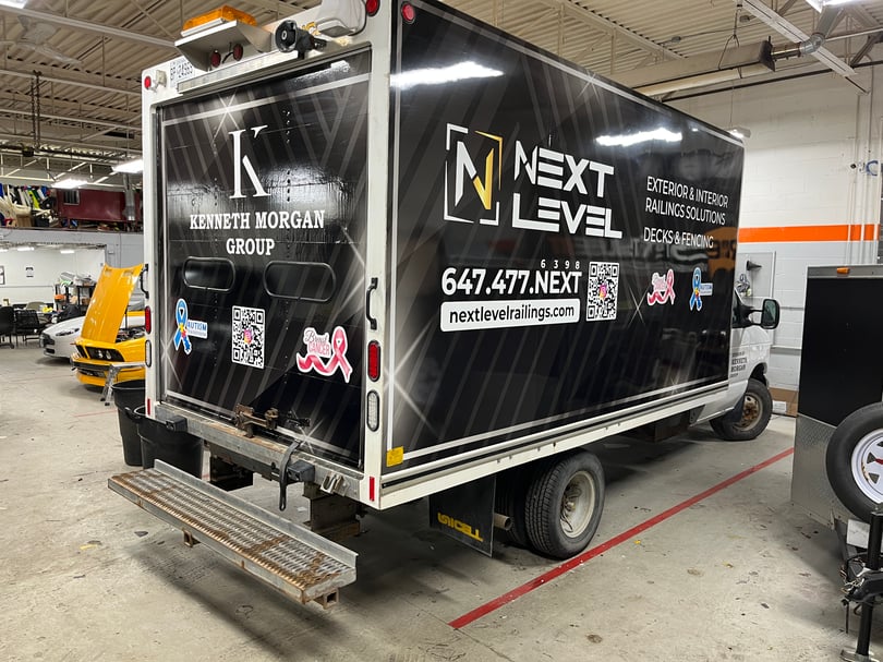 Black commercial branding wrap across a box truck body and rear doors