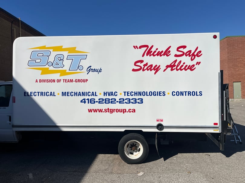 White S and T Group enclosed trailer with company logos, service categories, safety slogan, phone number, and website