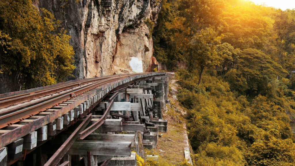 Railway on the side of a cliff with green treet below