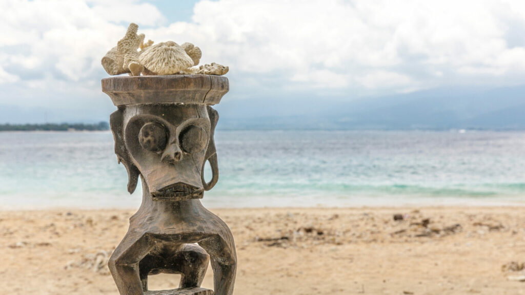 Wooden offering statue on the beach og Gili Meno