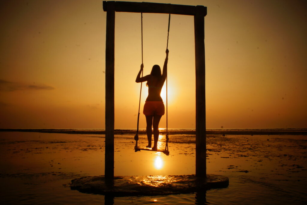 A women at one of the Gili swings at sunset