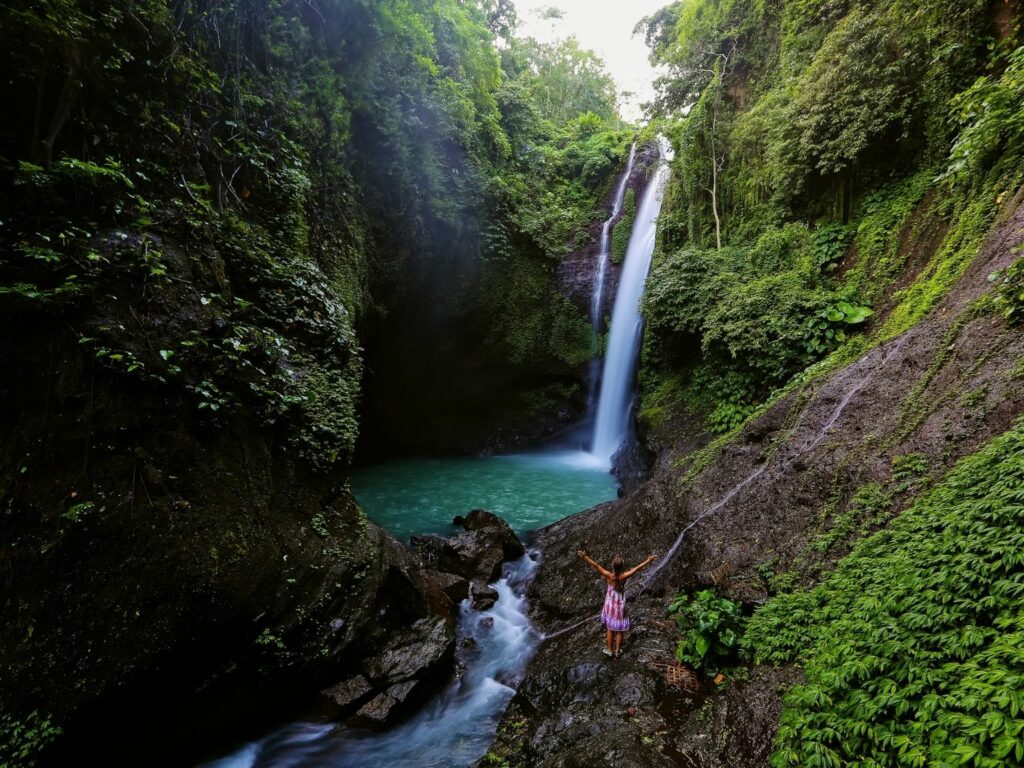 Woman with her hands up enjoying the view of Aling Aling Waterfall, Bali