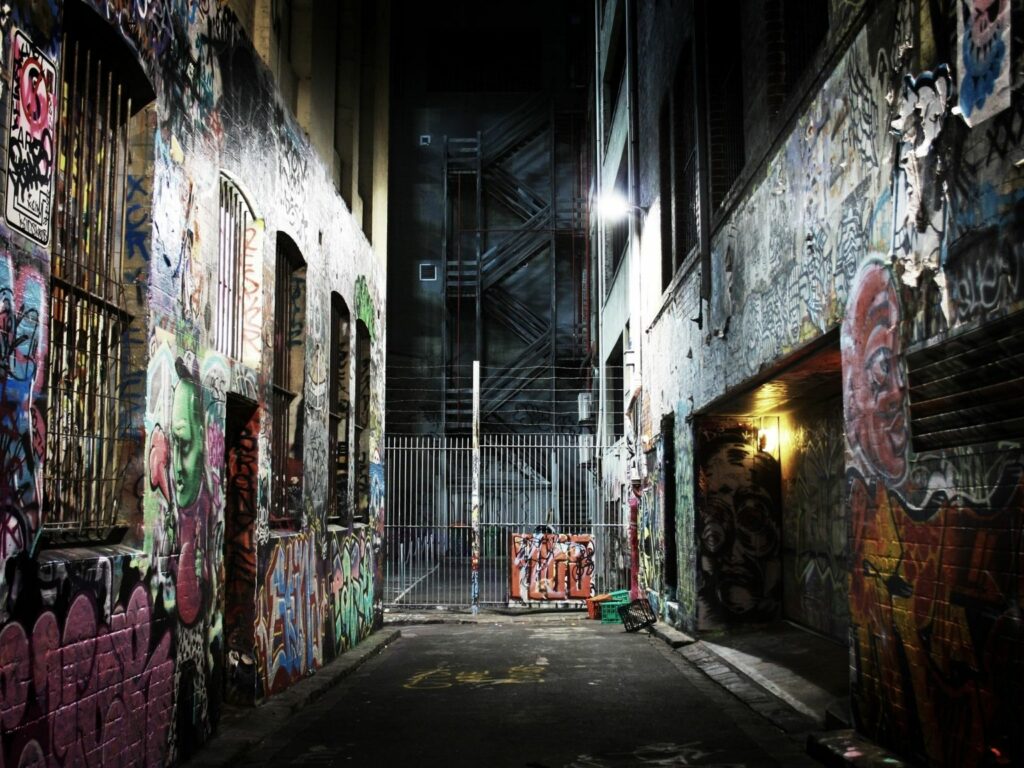 An alley in the dark with buildings covered in graffiti