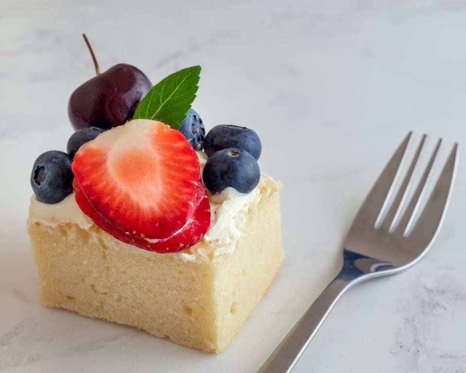 Cake with red fruits on top, and a fork on the side.