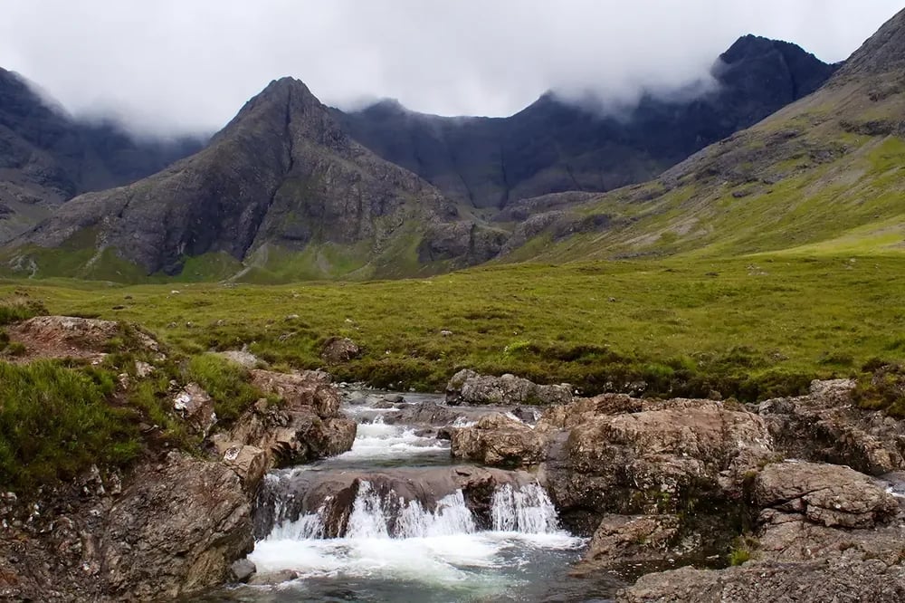 Deborah's earlier landscape — Cuillin ridge with a small waterfall in the foreground under an overcast sky.