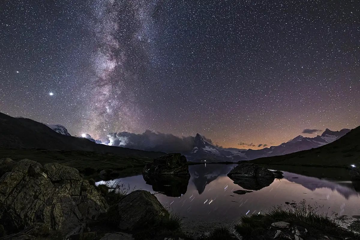the milky way over the top of snow capped mountains at night