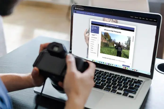An iPhotography Member studying the Off Camera Flash Photography course on their laptop, camera in hand — learning and doing in the same moment.