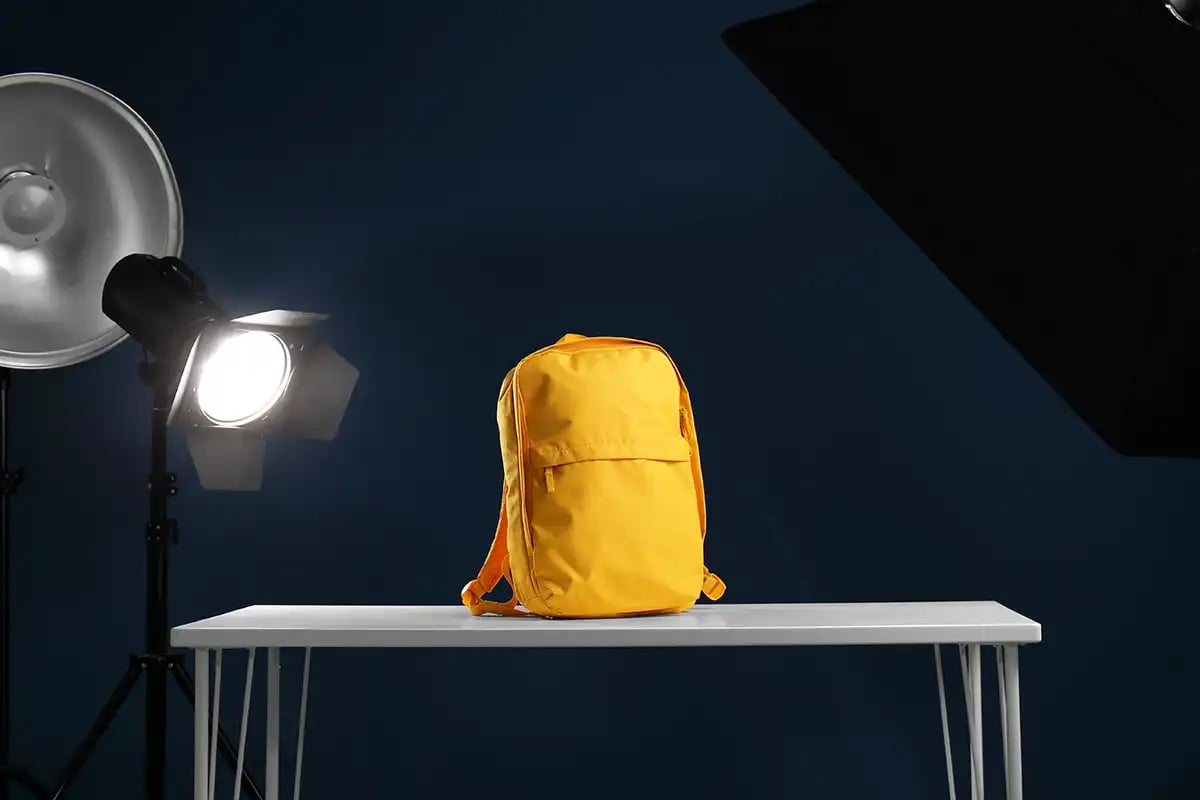 A yellow rucksack on a table surrounded by photography lights