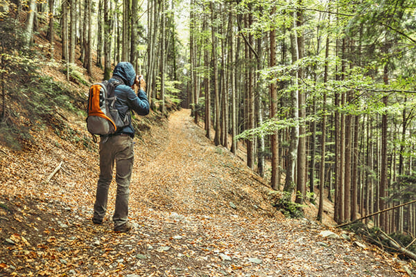 how to motivate for photographers blog image man taking a photograph in woodland blue coat orange bag