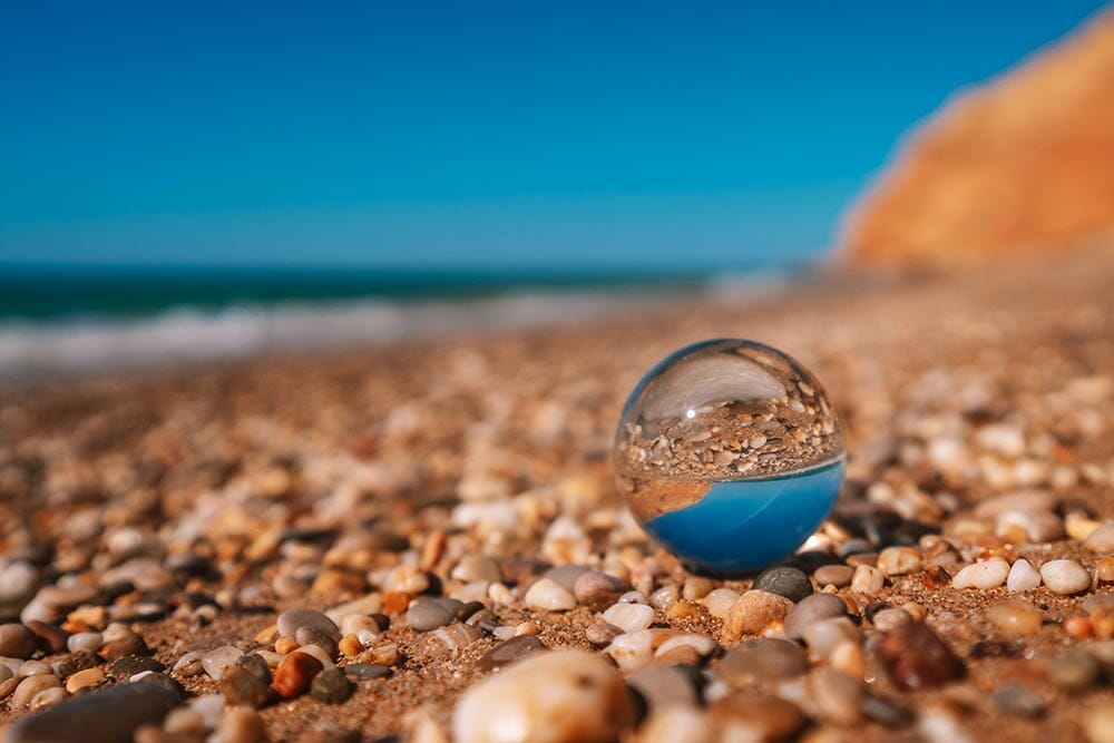 Beach with sea photographed through a crystal ball. The picture in the ball is in focus and the background is out of focus.