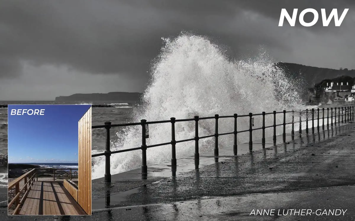 black and white photo of a wave crashing against the side of a promenade