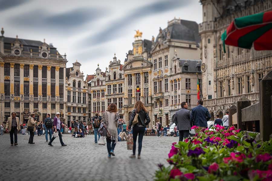 The Grand-Place in Brussels, with gilded guild houses around the cobbled square and people walking across it