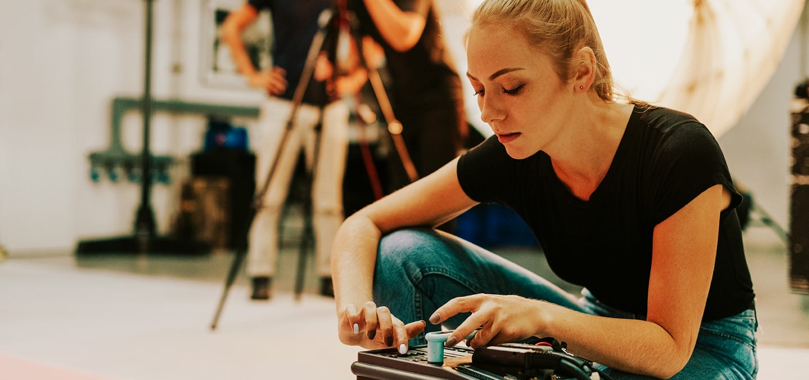 a female photographer changing the settings on a broncolor lighting power pack in a photography studio