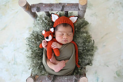 Cute little fox Newborn photography. Baby disguised as a fox. Sleeper child Christmas Santa cap, two week old.