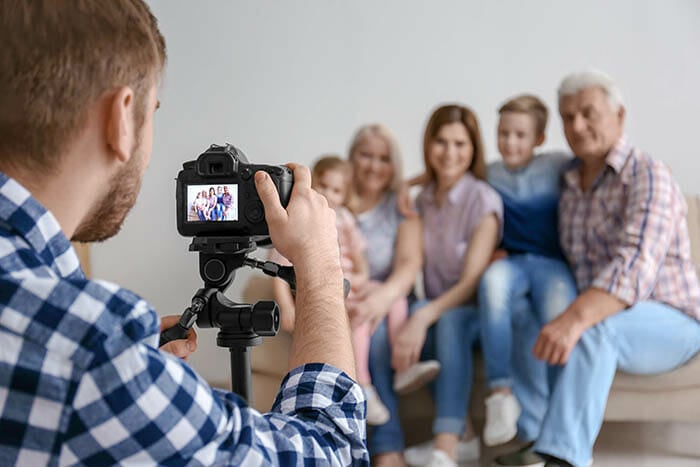 A male photographer taking photos of a family indoors