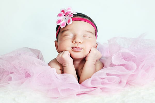 Newborn baby girl posing in tutu skirt and flower head band