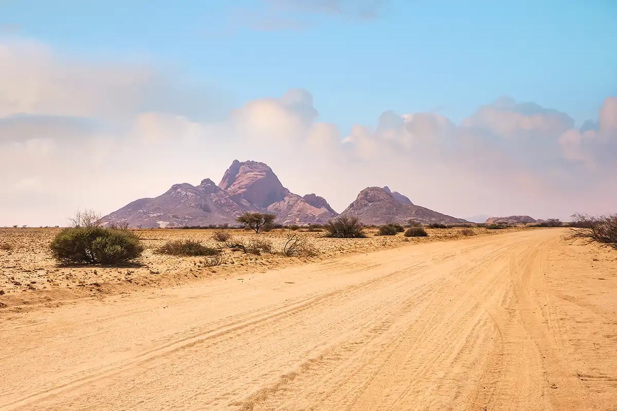 A desert road with mountains the background