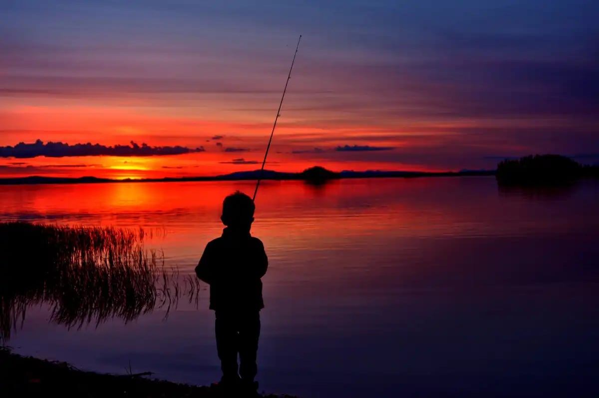 young boy fishing at sunset