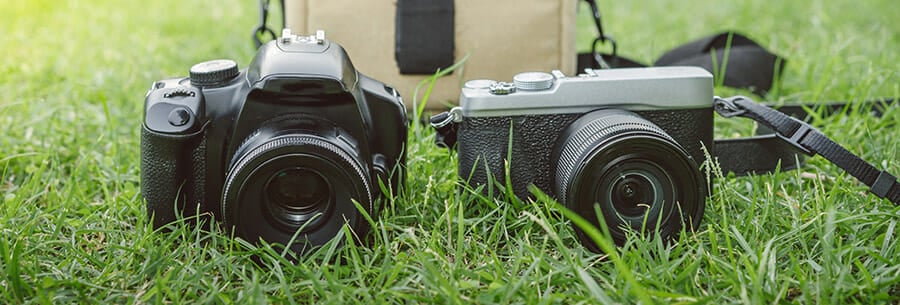Two digital cameras on the grass in a field