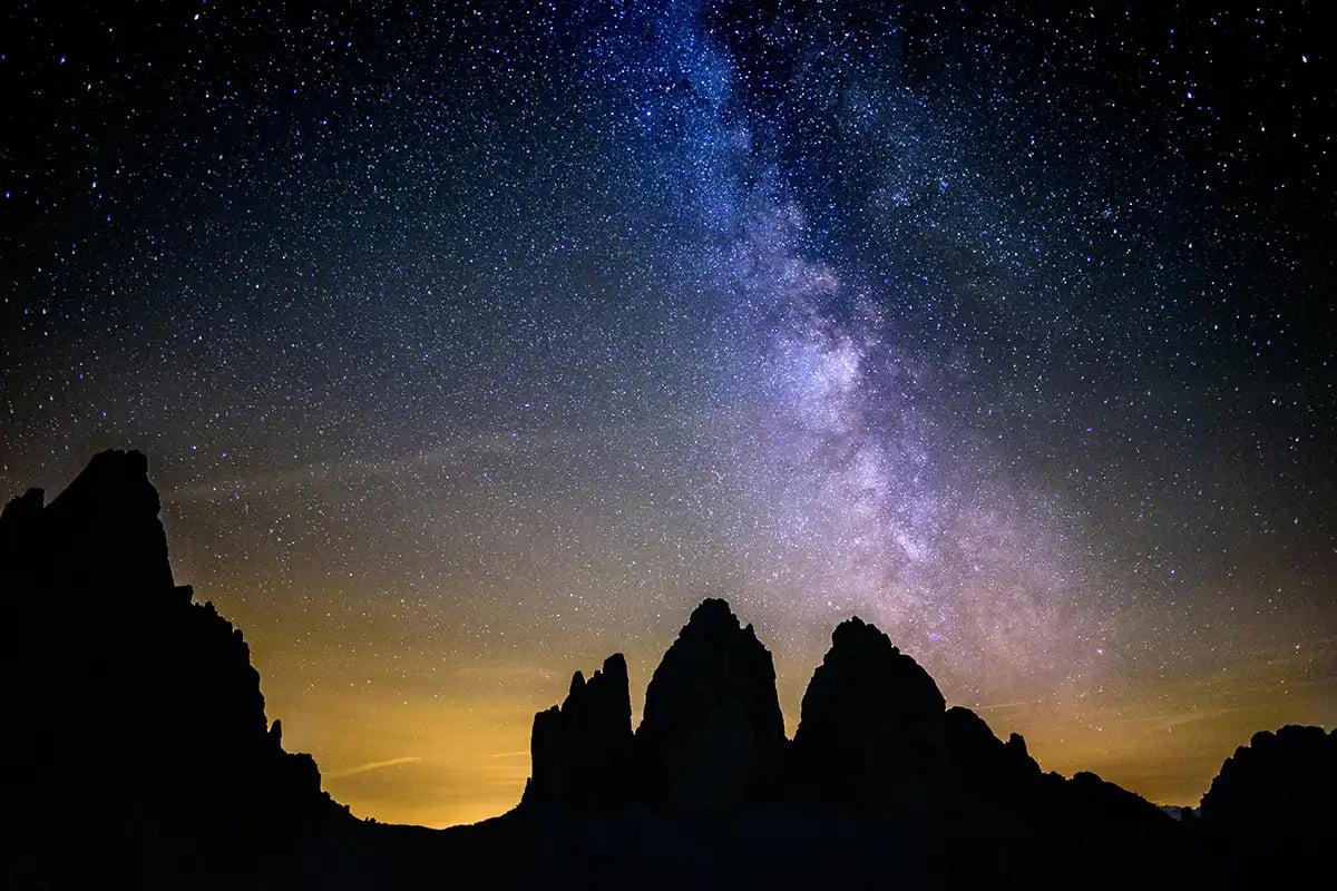 the milky way behind dark mountains at night