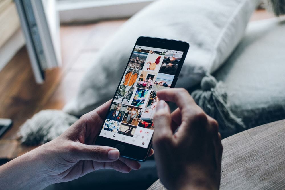 Young woman holding smartphone with search page screen of Instagram application. Instagram is largest and most popular photograph social networking.