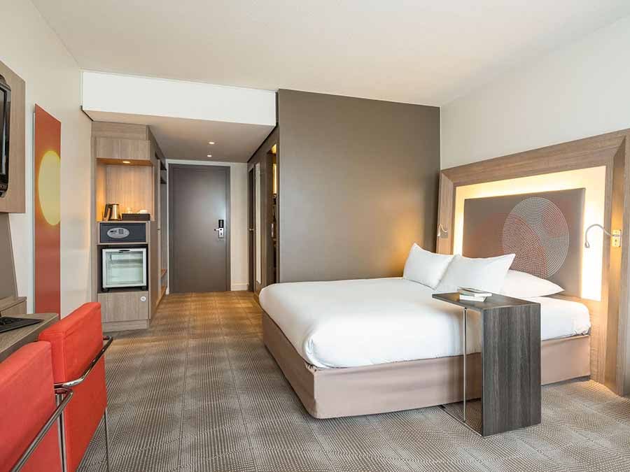 A bedroom at the Novotel Brussels City Centre, with a double bed, desk and tea-making area