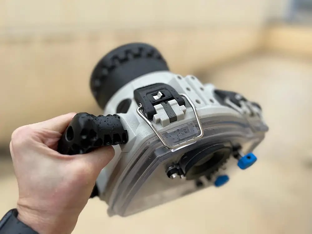 A hand holding an underwater housing case for underwater photography