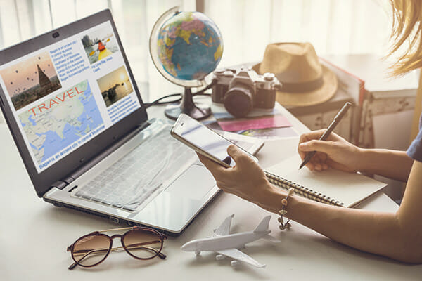 how to motivate for photographers blog image lady planning a trip in front of laptop with camera travel
