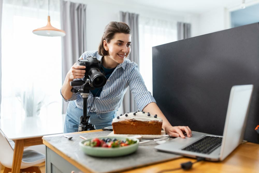 A behind-the-scenes shot of a food photographer at work with a cake set-up &mdash; food photography from the iPhotography Home Projects Course.
