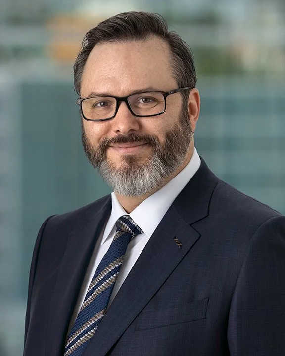 Casual business headshot of a smiling man with short brown hair and trimmed beard, wearing a white button-up shirt in an outdoor setting with light-colored rocks—photographed by Idaho Photography Studios.