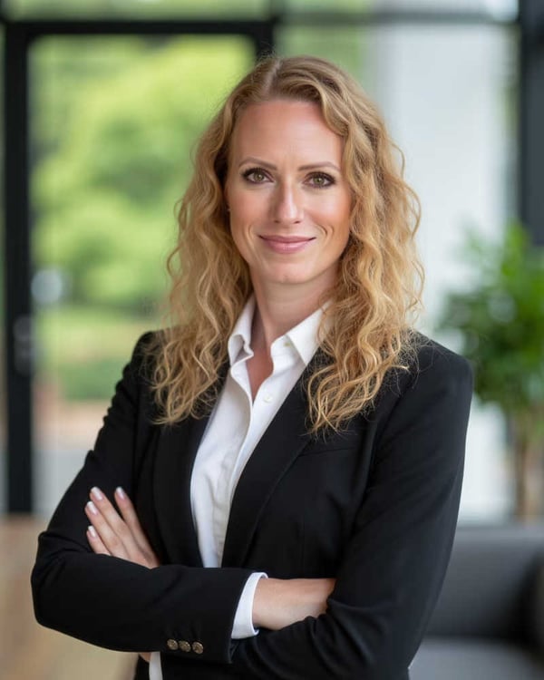 Modern professional headshot of a businesswoman with arms crossed in a contemporary office setting.