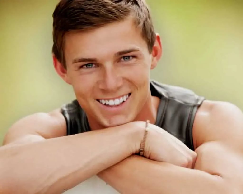 Emmett High senior in sleeveless gray shirt smiling outdoors with arms resting on a white surface and greenery in the background