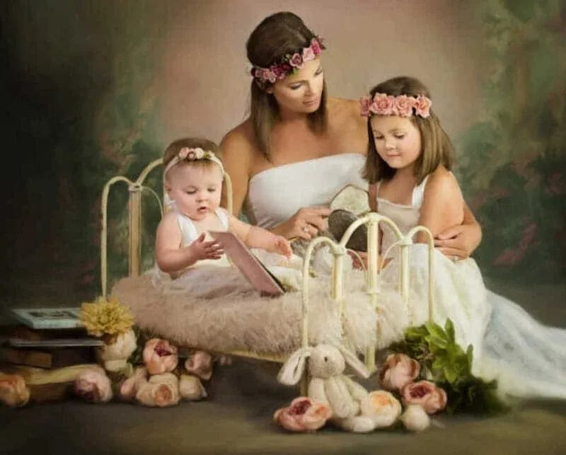 Woman and two children in white garments gathered around a vintage bed with a baby, surrounded by flowers and books — fine portrait in Old Masters style, captured in Idaho.