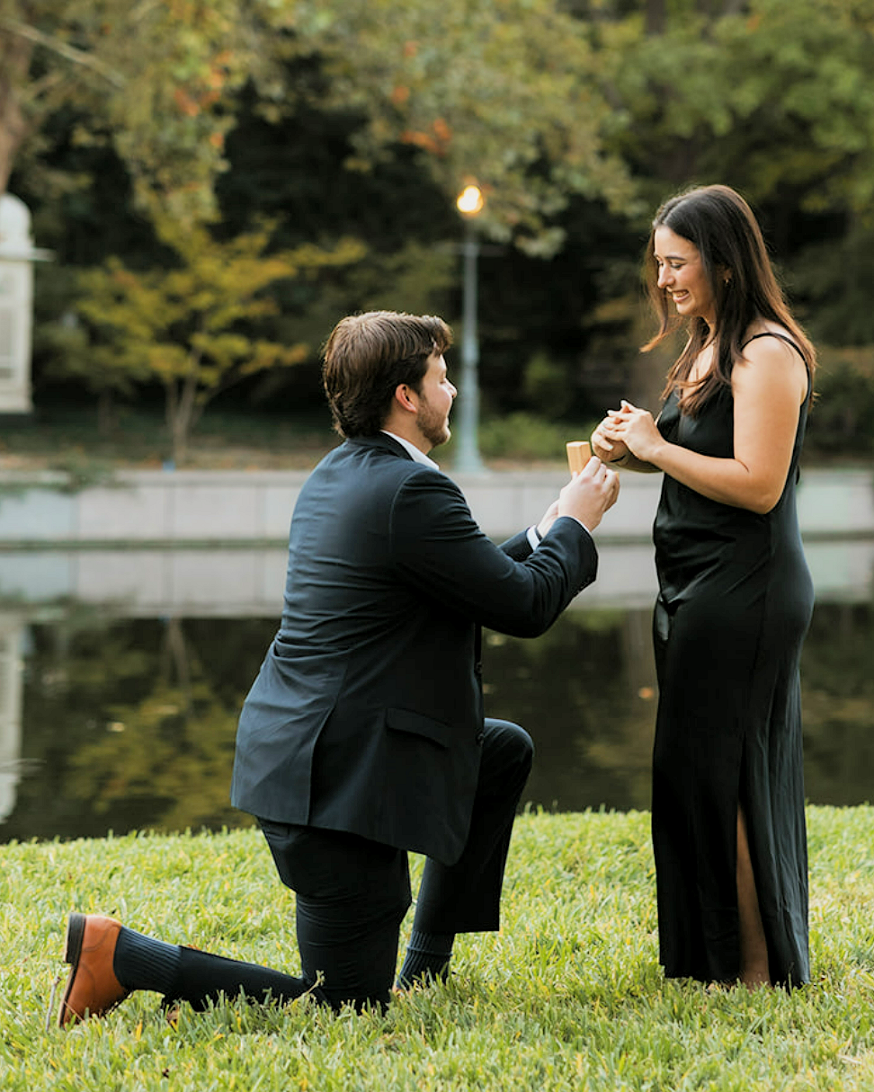 Idaho proposal photography in the park showing groom on one knee presenting a ring during an outdoor engagement moment