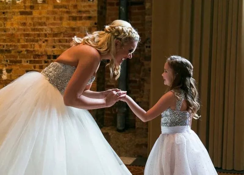Bride and flower girl share a joyful moment before the ceremony, captured by Idaho Photography Studios.