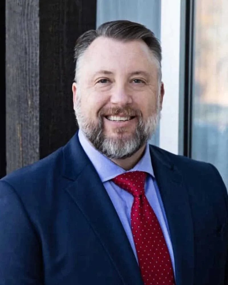 Professional headshot photography by Idaho Photography Studios featuring a confident business professional in a navy suit and red tie.