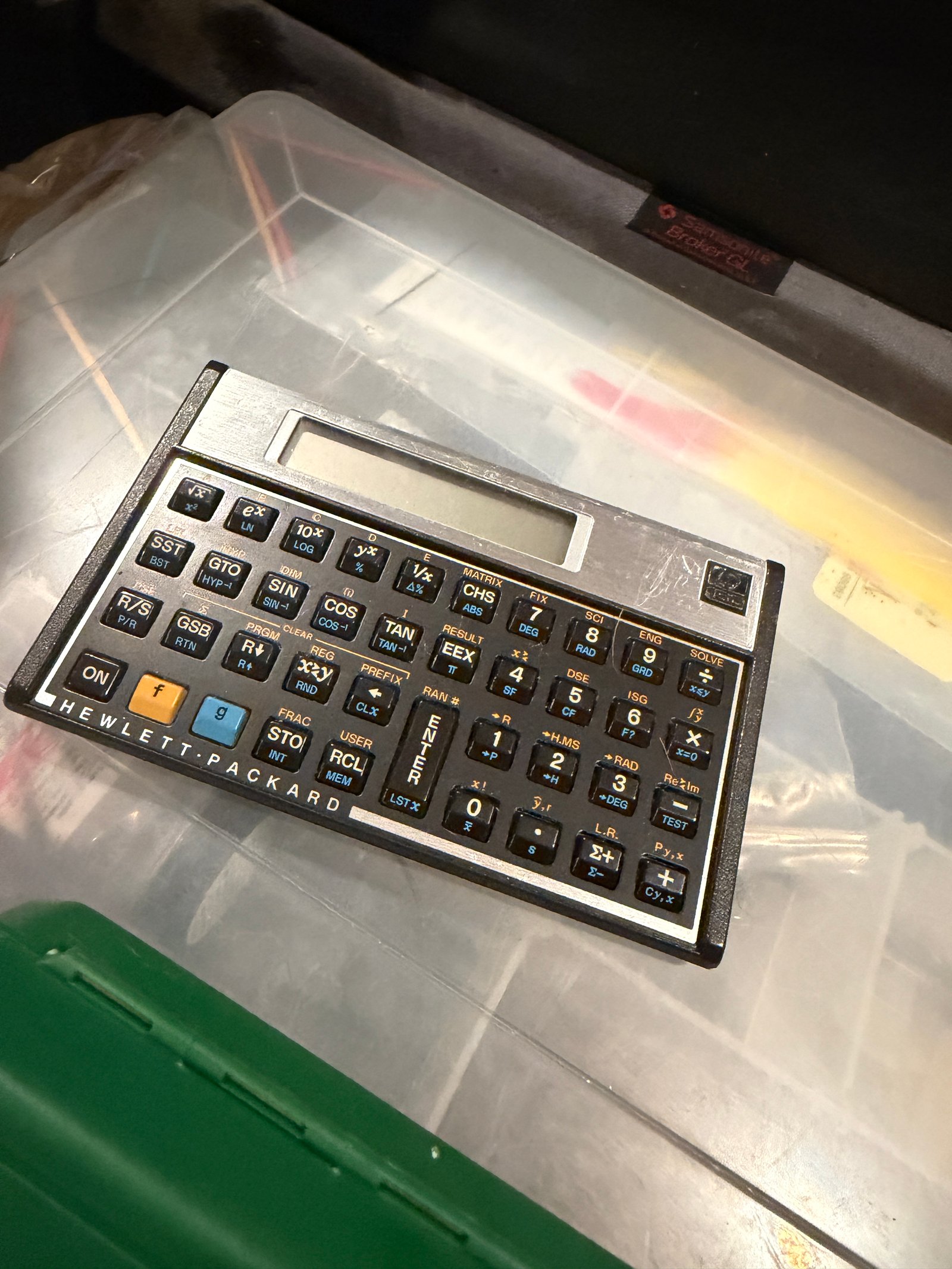 An old landscape-format Hewlett-Packard scientific calculator resting on a plastic storage bin