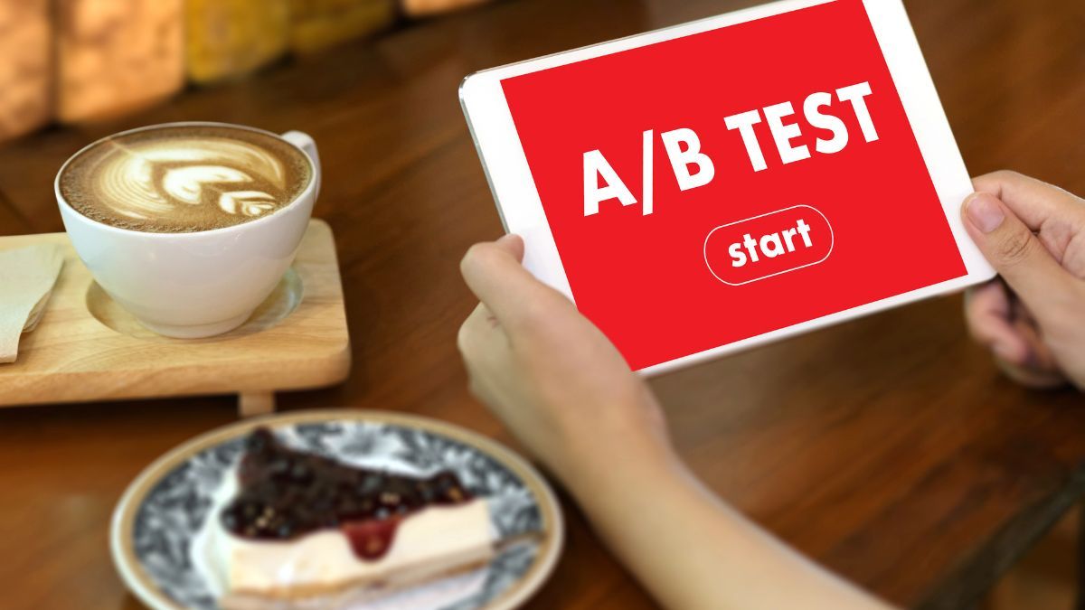 Tablet displaying 'A/B Test' next to a coffee and a slice of cake on a table.