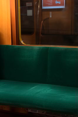 Train interior with velvet emerald green seats and honey wood wall and brass trims