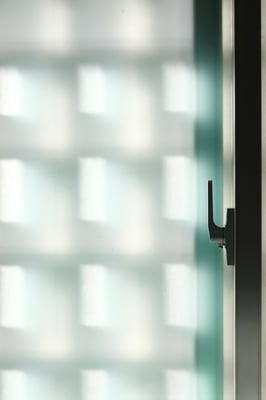 a door handle on a frosted glass door with diffused shadow in the shape of grids