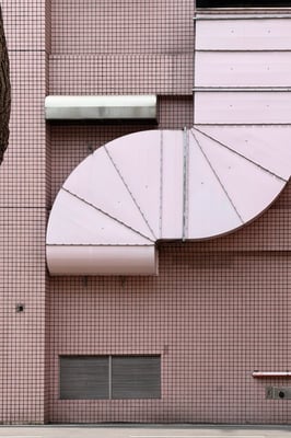 a giant pink spiral vent attached on the side of a pick square tiled building
