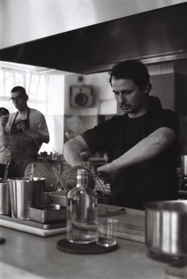 a person in a black shirt cooking in a kitchen