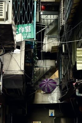 Dark narrow alley between buildings with tangled wires, purple striped umbrella, green sign “工作室”​​​​​​​​​​​​​​​​
